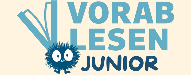 Banner mit dem Schriftzug „Vorablesen Junior" in Blautönen auf cremefarbenem Hintergrund. Links oben ist ein stilisiertes, aufgeschlagenes Buch als grafisches Element zu sehen. Darunter sitzt eine niedliche, runde Cartoon-Figur – ein dunkelblaues, stacheliges Wesen mit großen weißen Augen und einem freundlichen Gesichtsausdruck, das an ein Igel-Monster erinnert. Das Wort „Junior" ist in dunkelblauer, kindgerechter Schrift gesetzt.